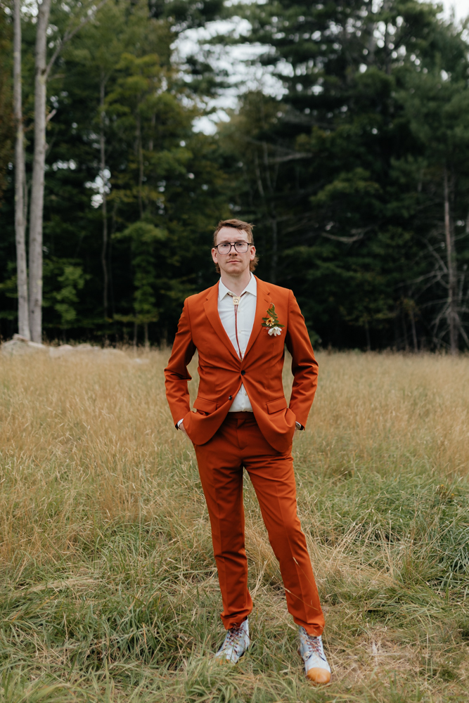 Groom in a burnt orange suit wedding day in the adirondacks