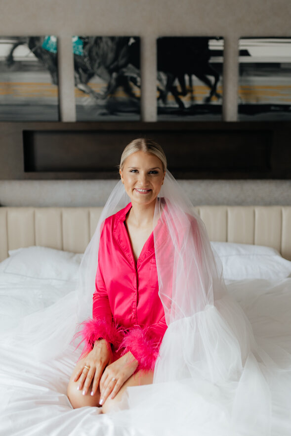 Bride in a pink robe getting ready on her wedding day