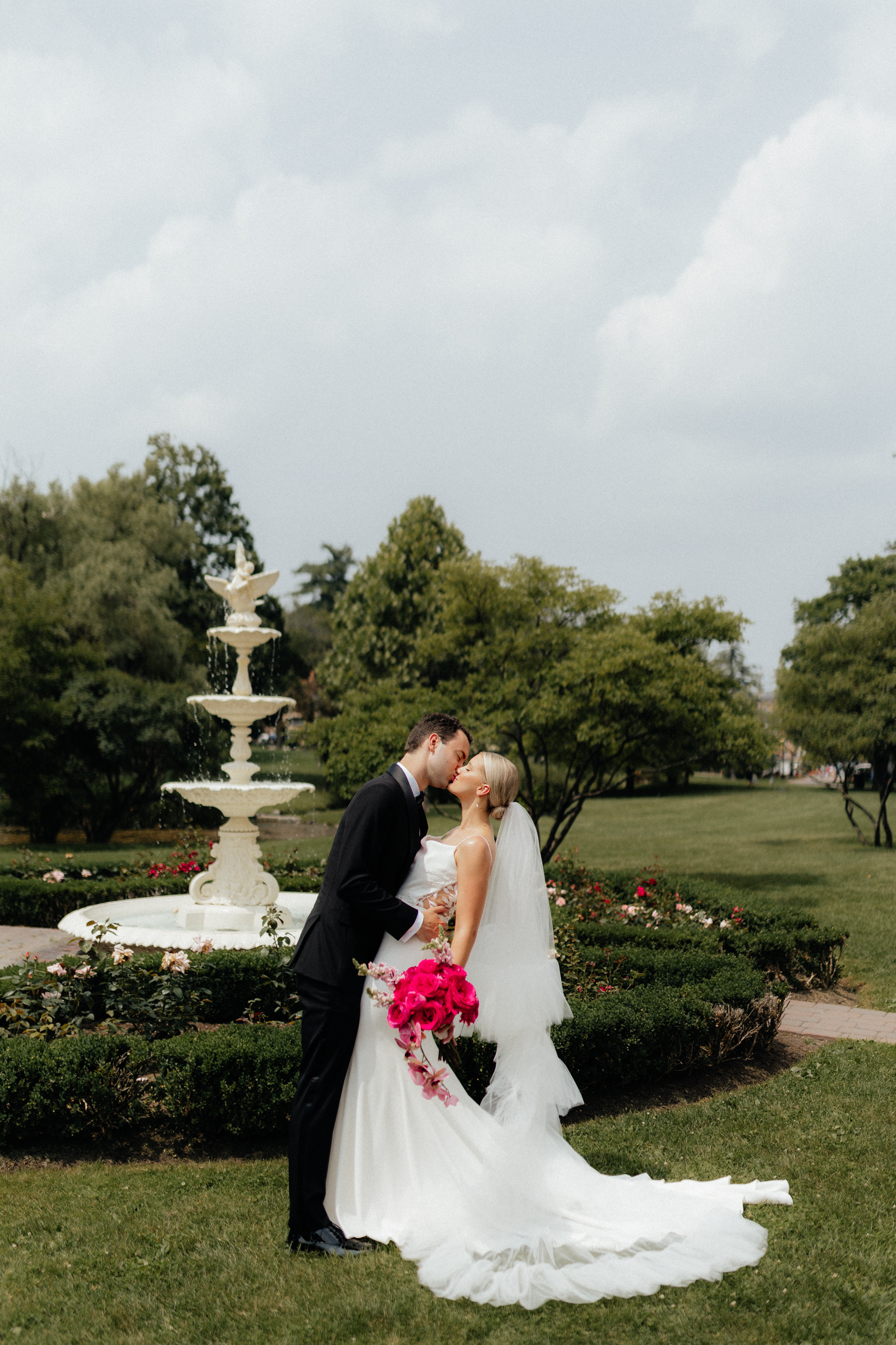 Elegant bride and groom kissing in front of a fountain