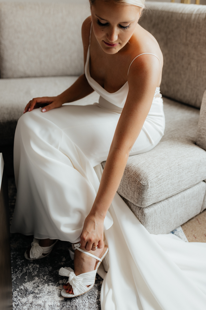 Elegant bride puts on her shoes on her wedding day