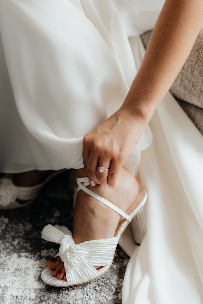Elegant bride puts on her shoes on her wedding day