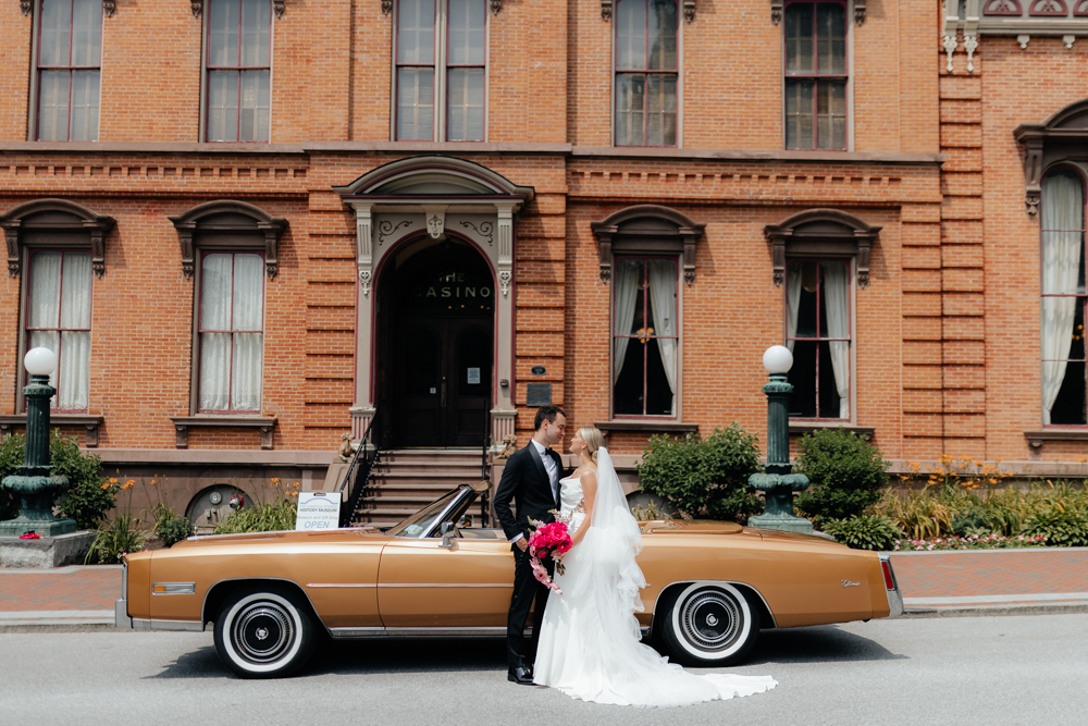 Elegant bride and groom on their wedding day with a tan vintage car