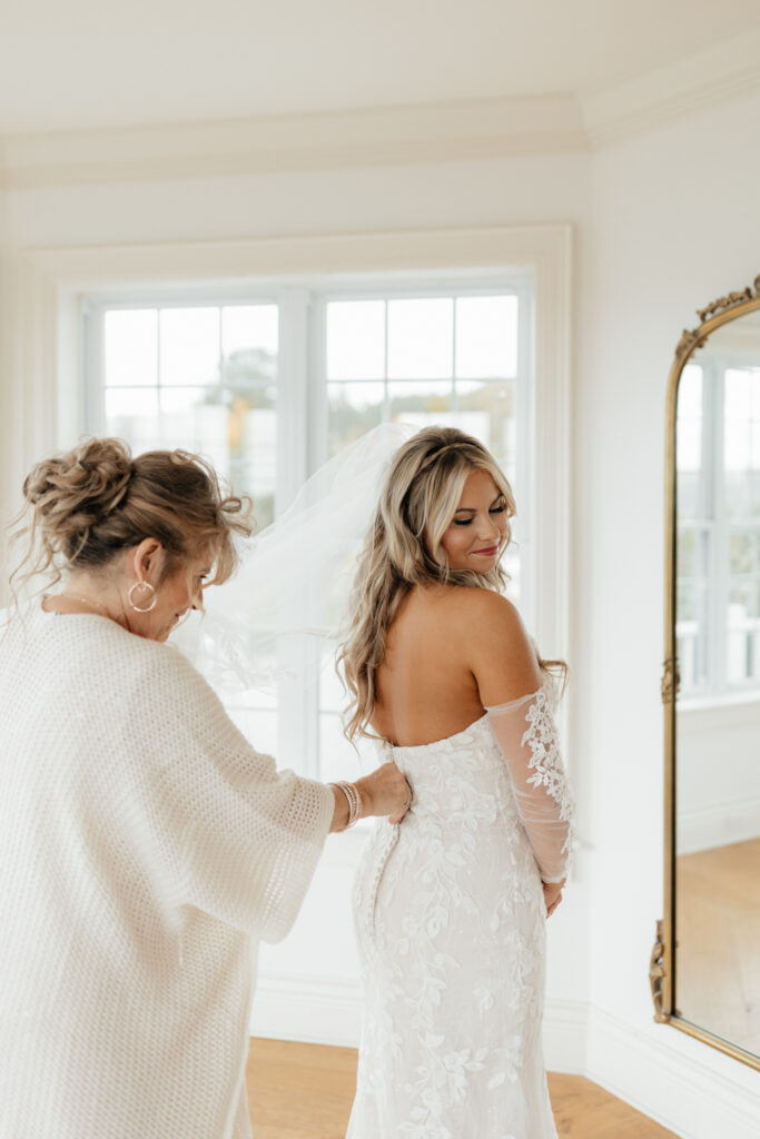 Bride's mom helping bride get in her dress on her wedding day