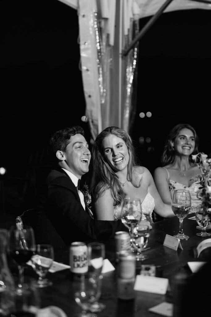 Bride and groom laugh during toast in their tented reception