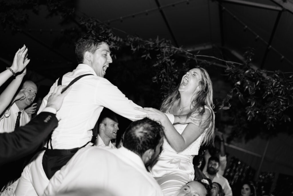 Bride and groom laugh while dancing in their tented reception