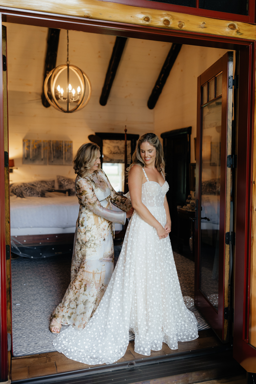 mom helping bride in her dress on her wedding day