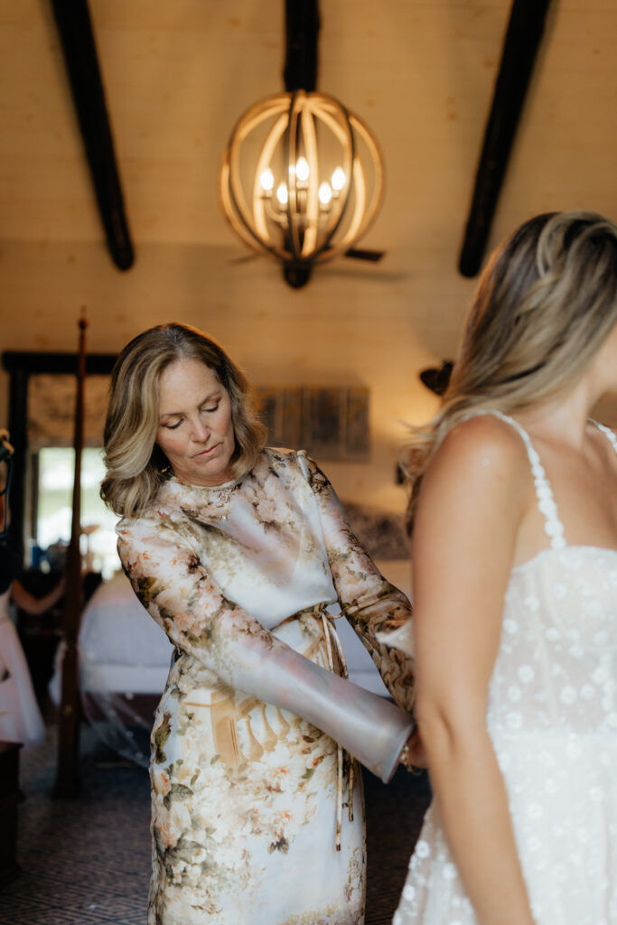 mom helping bride in her dress on her wedding day