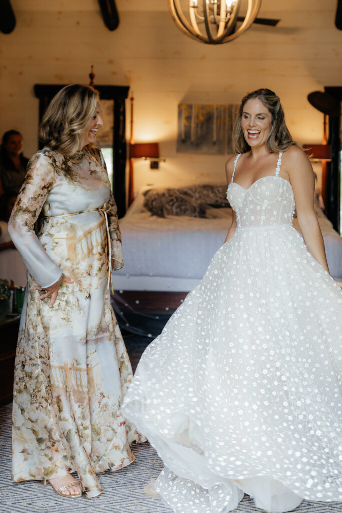 mom helping bride in her dress on her wedding day