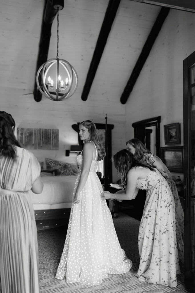 mom helping bride in her dress on her wedding day