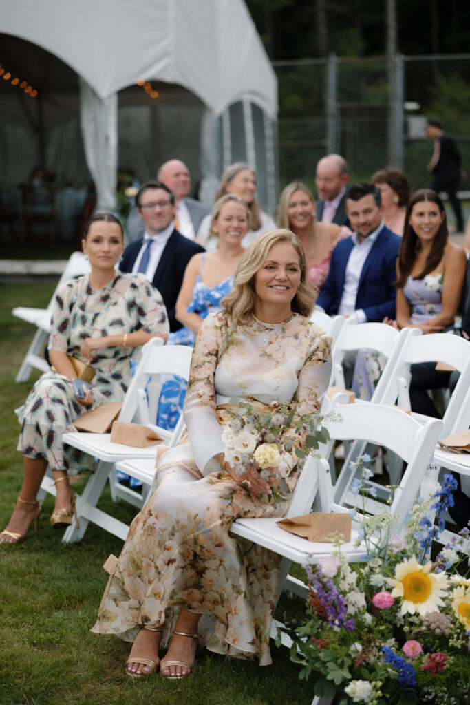 mom watches as bride arrives by boat to her lakeside ceremony in the Adirondacks