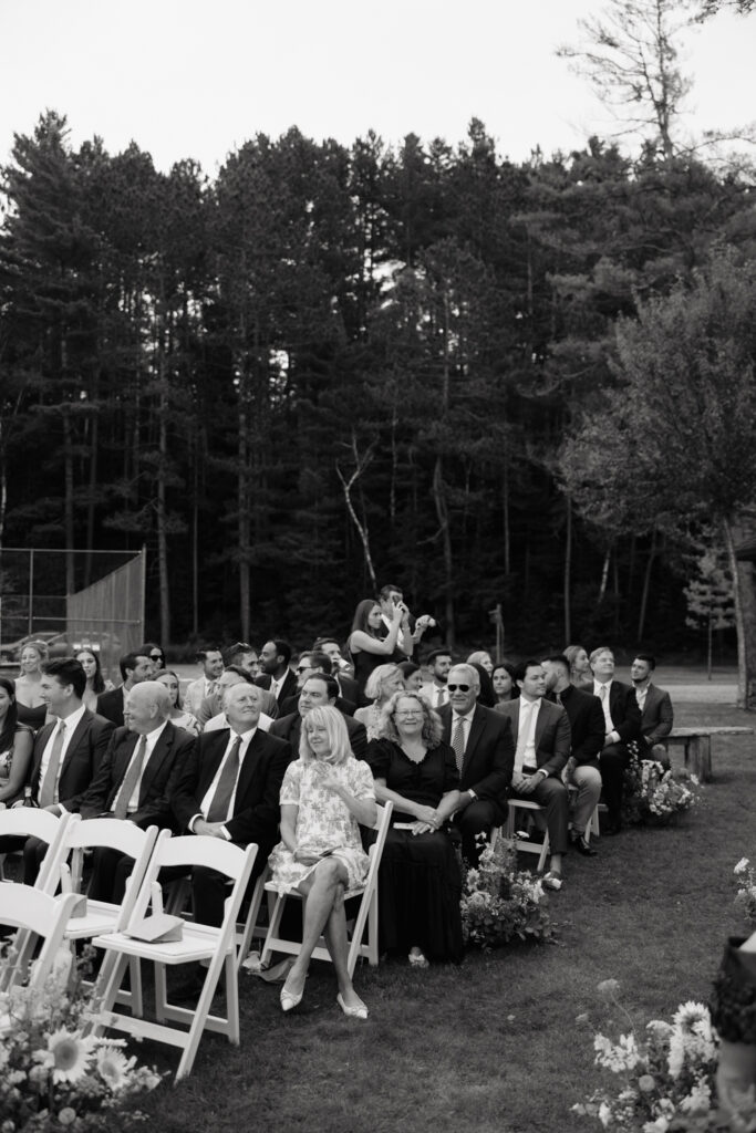 guests watch as bride arrives by boat to her lakeside ceremony in the Adirondacks