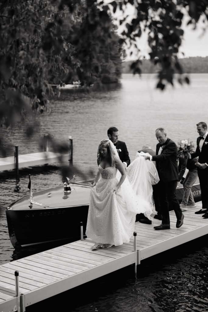 bride arrives by boat to her lakeside ceremony in the Adirondacks