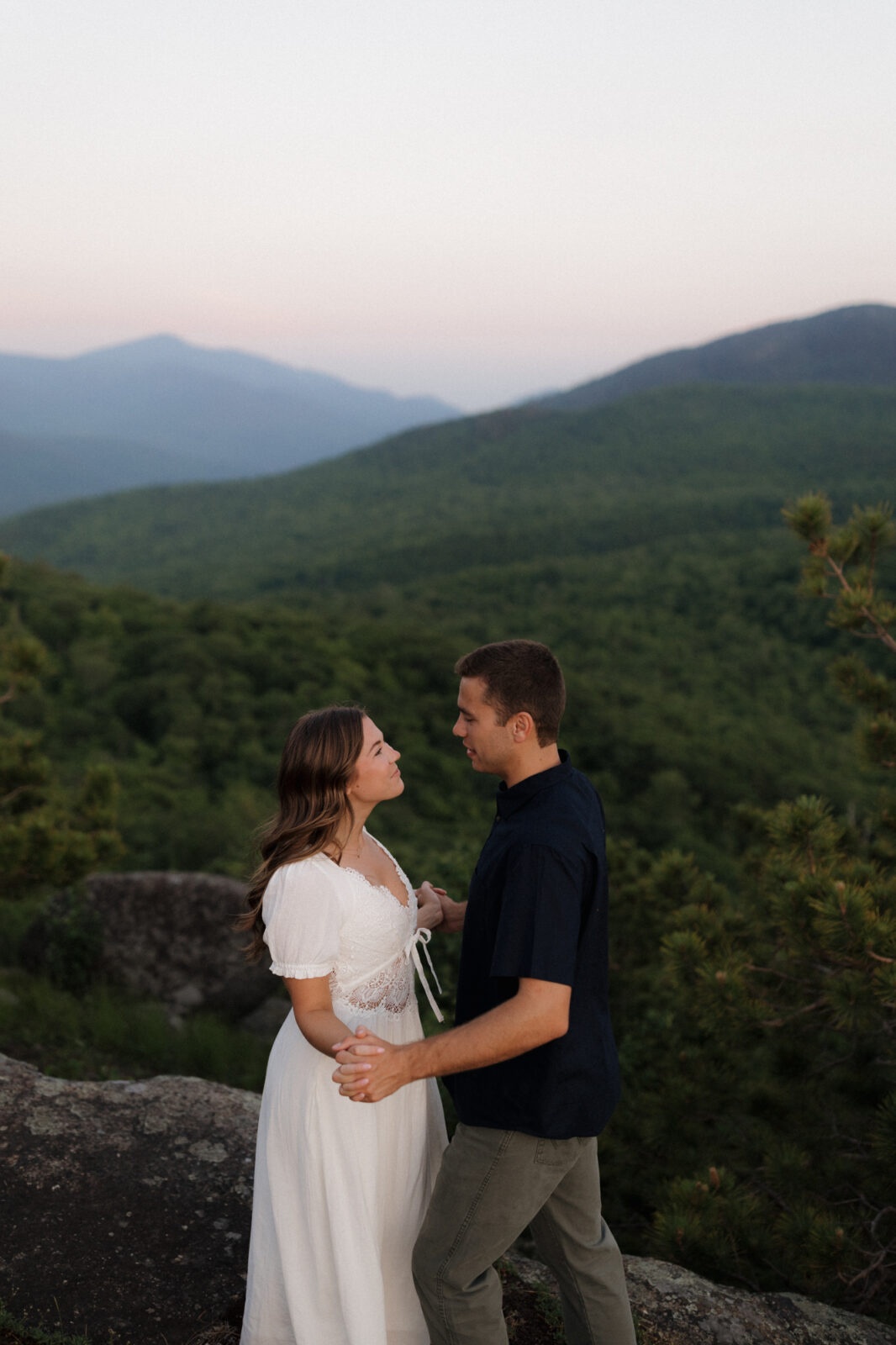 Engaged couple look lovingly at each other on top of a mountain