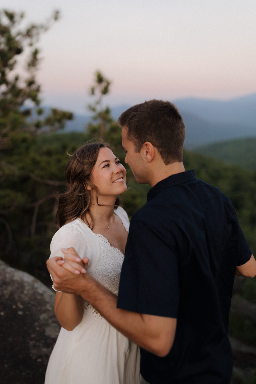 Engaged couple look lovingly at each other on top of a mountain