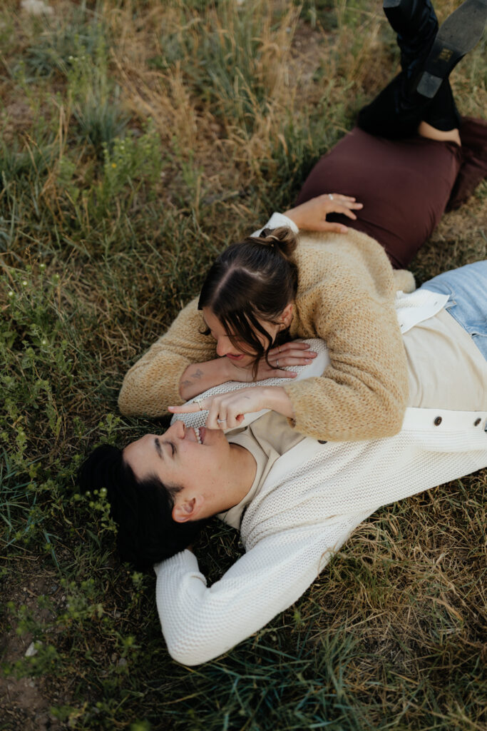 Couple lays in the grass at TIbble Fork Reservoir in Utah
